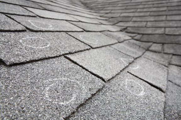 Close up of asphalt shingles with circles marking damage.