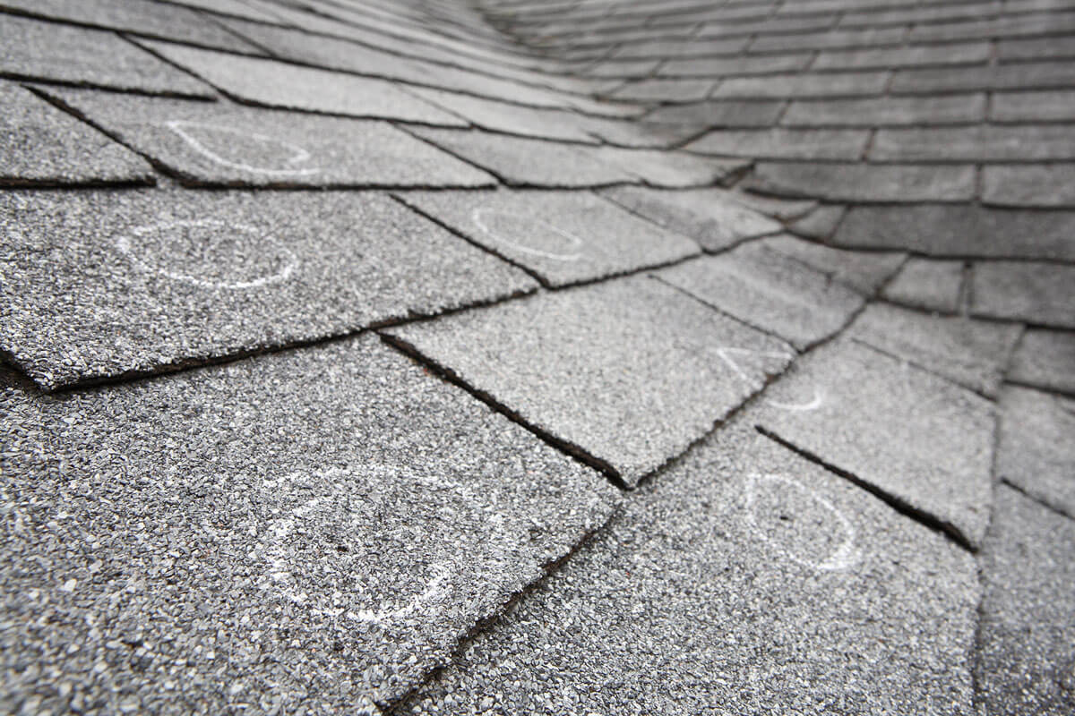 Close up of asphalt shingles with circles marking damage.